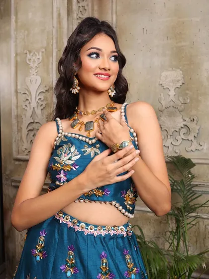 The details matter. The pearl-lined blouse, the unique jewelry, and the colorful makeup all come together to create a truly special sangeet look.
