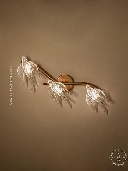 A close-up of our bird-themed wall sconce. Three delicate glass birds are mounted on a small rose-gold branch, providing a soft, ambient light. It's a charming accent piece that complements the larger chandeliers in the series or stands beautifully on its own.