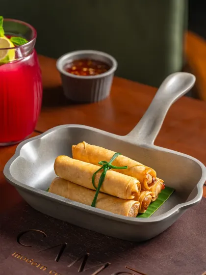 A close-up of the spring rolls at Camo, tied with a chive for a unique presentation.