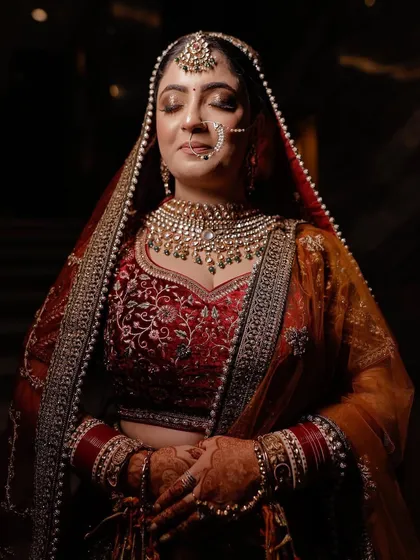 A serene moment captured, with the bride looking down. The lighting beautifully highlights the craftsmanship of her bridal jewellery.
