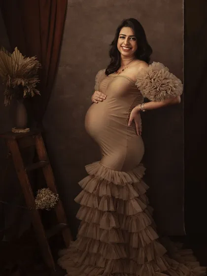 The rich textures of the gown and the warm, earthy backdrop come together to create a portrait that is both glamorous and deeply soulful.