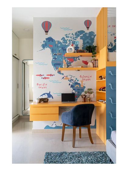 The study area in the children's room, seamlessly integrated with the bunk bed structure and world map wallpaper. The design provides a comfy and inspiring spot for learning and creativity.