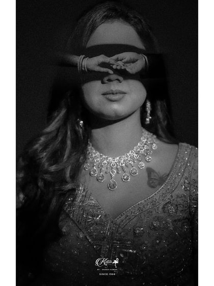 A creative black and white portrait of a bride with her eyes covered by a reflection of hands, creating an artistic and surreal image.