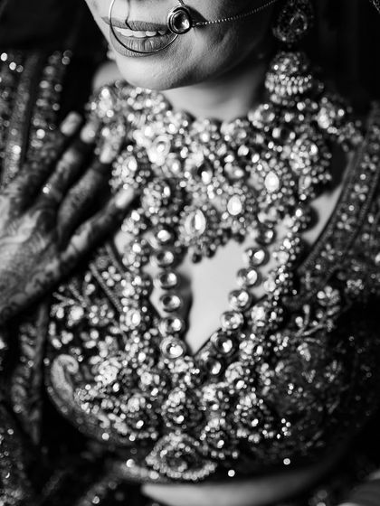 A dramatic black and white shot focusing on the intricate jewelry and the bride's smile. Details are everything.