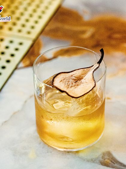 A simple yet elegant pear-garnished cocktail on a marble surface. This image highlights our focus on quality ingredients and clean, artistic presentation.