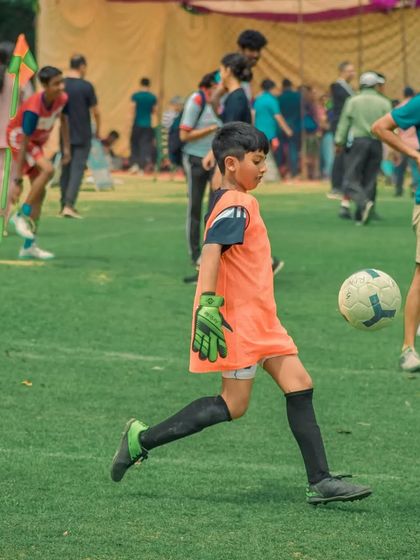 A young goalkeeper kicks the ball out of his hands to restart play.