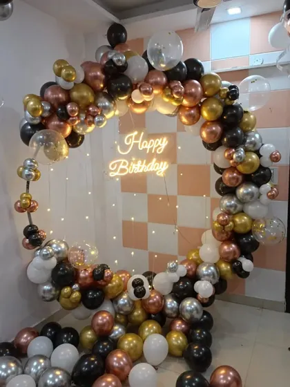 A full circular balloon arch in black, white, and mixed metallics, complete with a neon sign and fairy light curtain. This versatile design can be adapted for any anniversary party, offering a complete photo-ready backdrop.