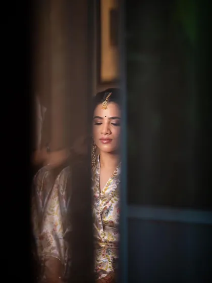 A quiet, reflective moment during the getting-ready process. The soft, natural light highlights the subtle glow of her skin.