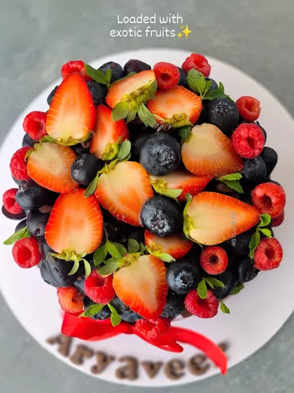 An aerial view showcasing the vibrant pile of fresh strawberries, blueberries, and raspberries that top the KitKat cake. The combination of rich chocolate and tangy fruit is a classic favorite.