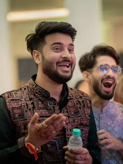A candid shot of the groom and a friend reacting with excitement during a performance. Capturing guest reactions is key to telling the full story of the event.