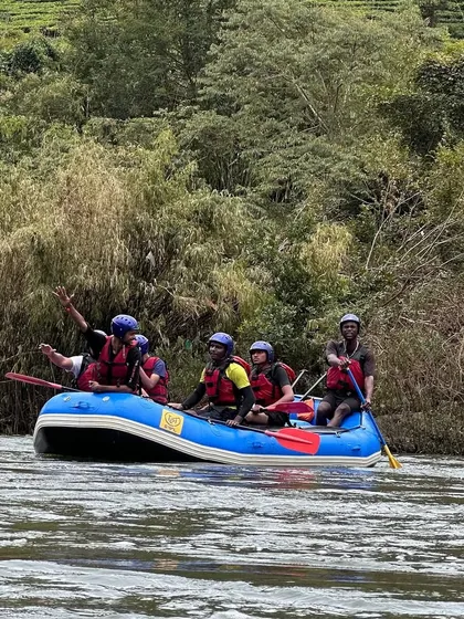 A participant waves enthusiastically from the raft, capturing the pure joy and excitement of a day spent on the river in Coorg.