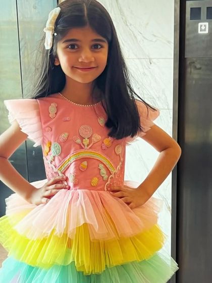 Happiness is a Candyland party. This little girl is all smiles in her custom dress, featuring a candy-embroidered bodice and a rainbow-layered tulle skirt.