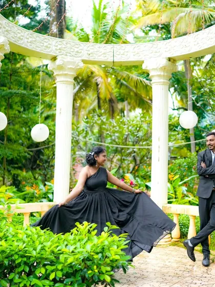 A stylish pose in a garden gazebo. The bride's flowing black gown spreads out beautifully, creating a dramatic and elegant pre-wedding photo.