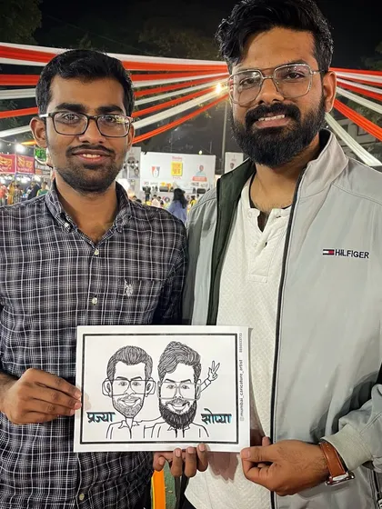 Two friends with their caricature at a lively outdoor event in Mumbai.
