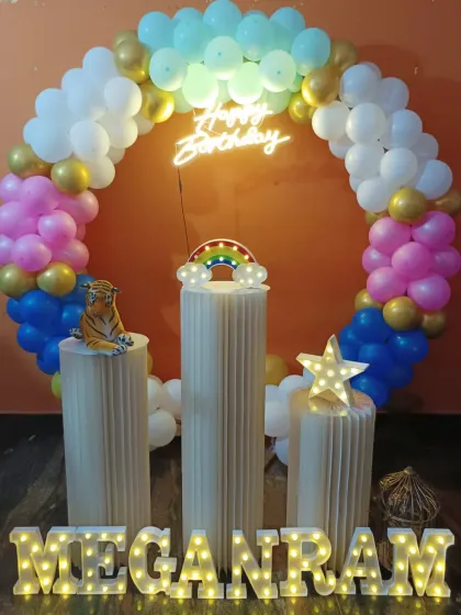 A simple and sweet birthday setup with a circular balloon arch in pastel colors. This decoration features a neon sign, pedestals, and a small tiger prop for a touch of fun.
