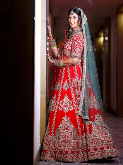 A full-length shot of the bride, showcasing her beautiful smile and the flow of her traditional wedding lehenga.
