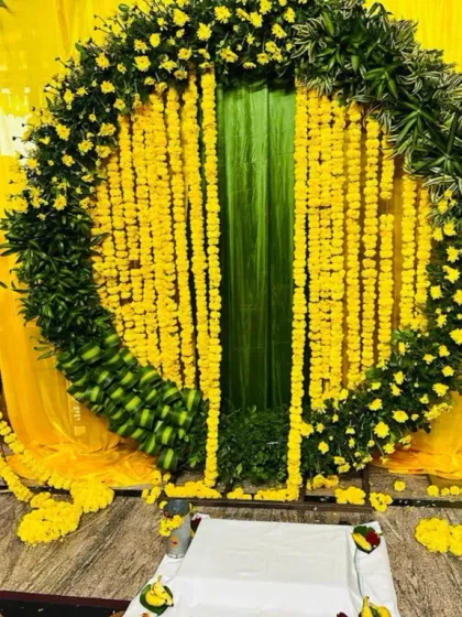 A close-up of the Haldi backdrop, showing the detail of the marigold strings and the base of the arch, which is made from small, green bananas for a completely natural and traditional touch.