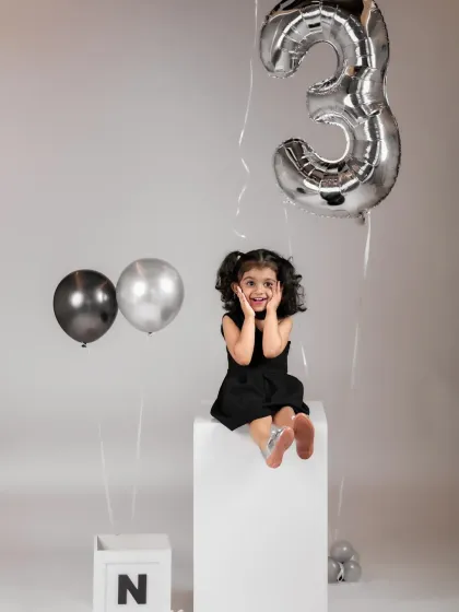 The big THREE. This little girl's joyful expression is perfectly captured in a simple and modern birthday setup with silver balloons.