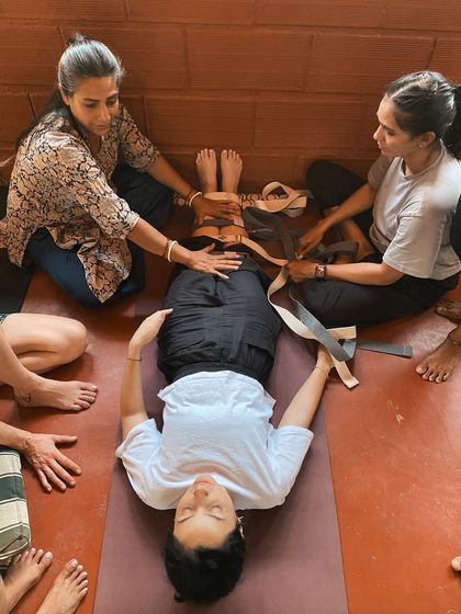 Learning to work with others is essential for a yoga therapist. Here, students practice adjusting a fellow student in a supported supine pose, using straps to stabilize the hips and create a gentle, healing opening.