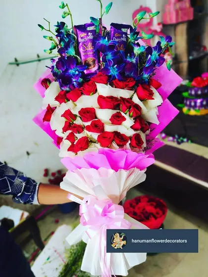 I love creating bouquets that are also a complete gift. This arrangement combines classic red and white roses with exotic blue orchids and includes Cadbury Silk chocolates nestled among the blooms, all wrapped beautifully.