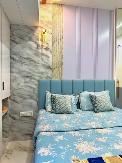 The headboard wall in this bedroom combines three different textures: a marble-finish panel, vertical fluted panels, and a soft blue upholstered headboard, creating a rich, layered look.