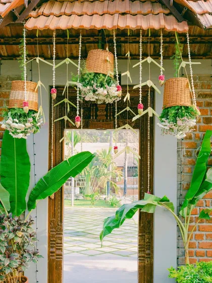 An entrance that whispers timeless charm. We used hanging wicker baskets filled with flowers, delicate jasmine strings, and large banana leaves to create a warm and inviting entryway for a Muhurtham ceremony.