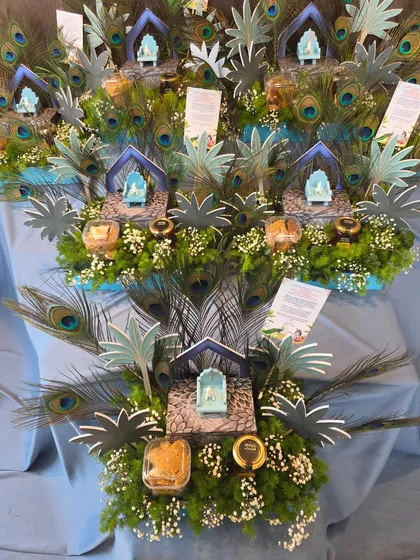 Another angle of the "Little Kanha" gift sets, showcasing the beautiful arrangement of peacock feathers and fresh greenery that forms the base for each hamper.
