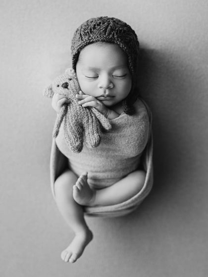 The same adorable pose in timeless black and white, which emphasizes the baby's form and the texture of the wrap.