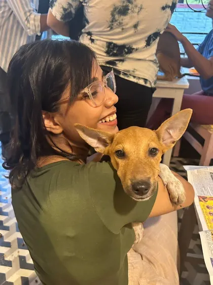A participant beams with joy while holding an adorable indie puppy with large, alert ears. These happy interactions are a common sight at our events.