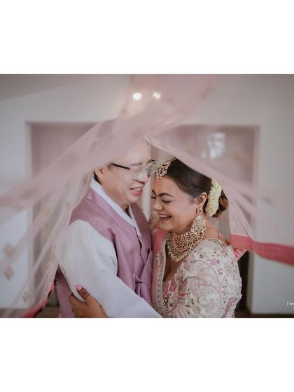 A heartwarming moment between a bride and her father, sharing a laugh under her veil.