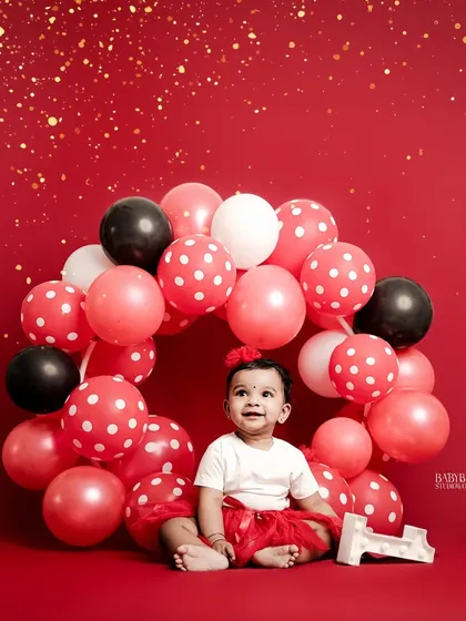 Turning one is a huge milestone! We love designing vibrant and fun first birthday photoshoots, like this one with a custom red, black, and white balloon wreath that makes your baby the star.