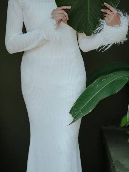 A creative fashion shot where the model's face is partially hidden by a large leaf. This adds an element of mystery and artistry.