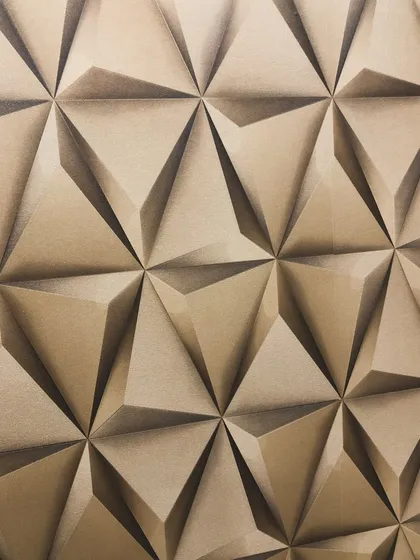 This close-up shows the detail of a 3D geometric wallpaper. The triangular pattern creates an illusion of depth and changes its look depending on the light, adding a modern and dynamic feel to any room.