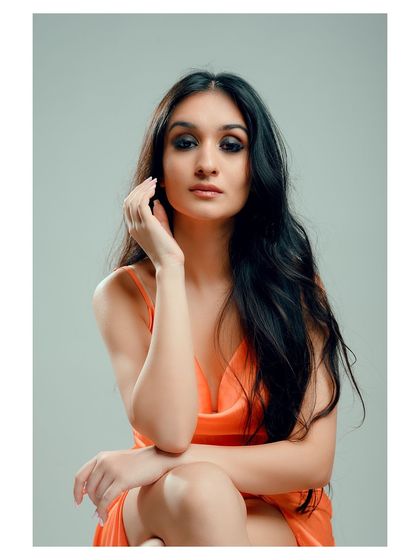 An elegant portrait in a vibrant orange dress. The seated pose is graceful, and the color of the dress stands out beautifully against the muted background.