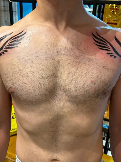 These tribal-style wings were designed to cover up some old marks on the client's chest, giving him a powerful and symmetrical new look.