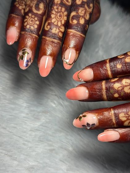 A delicate and modern bridal look. We did a soft peach ombre on her natural nails and added tiny, hand-painted floral stickers and a simple gold ring detail.