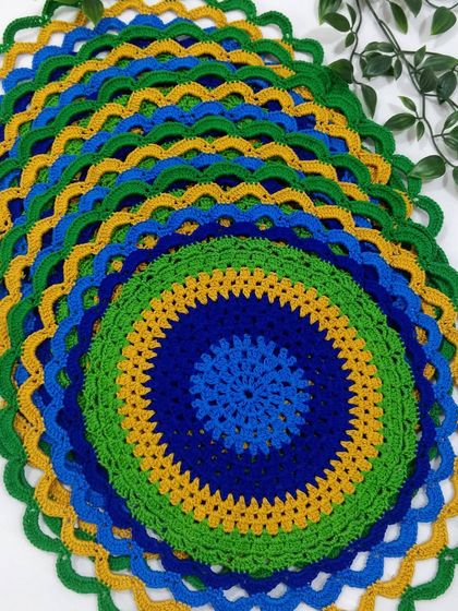 A stack of my peacock placemats, showing the beautiful layers of blue, green, and gold. They are made with high-quality cotton threads for durability.