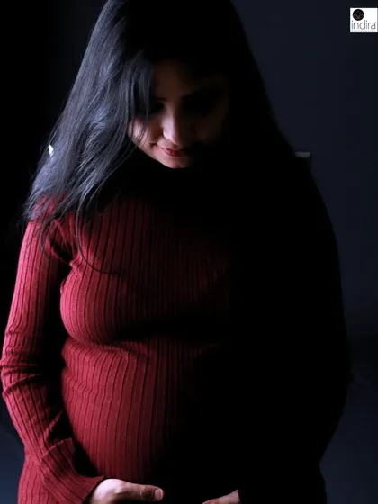 A beautifully lit, moody portrait of the mother-to-be looking down, highlighting the quiet and powerful connection with her unborn baby.