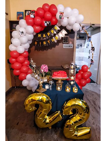 A classic red and white balloon arch sets the stage for this 22nd birthday party. We included large gold foil balloons of the number '22' to make the milestone clear, perfect for a fun and vibrant home celebration.