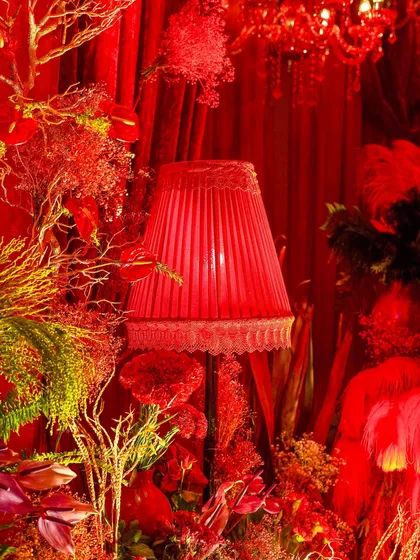 A close-up of the decor details. I layered different textures and shades of red, using florals, lighting, and fabrics to create a rich and immersive environment.