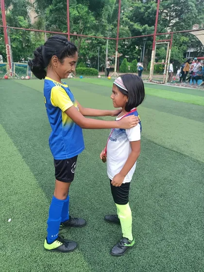 True strength lies in lifting others up. A player helps her teammate with her medal.