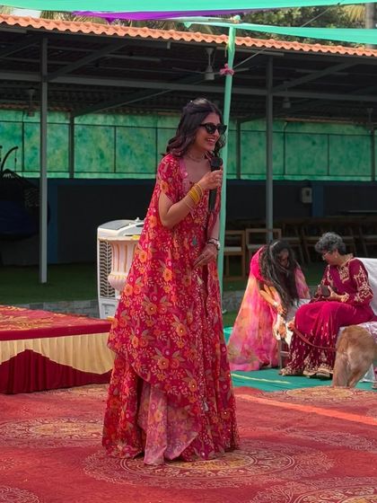 This pink floral print skirt and cape set is a fun and modern choice for a haldi or carnival-themed party. The handcrafted blouse and lightweight open cape are stylish, comfortable, and perfect for an outdoor event.