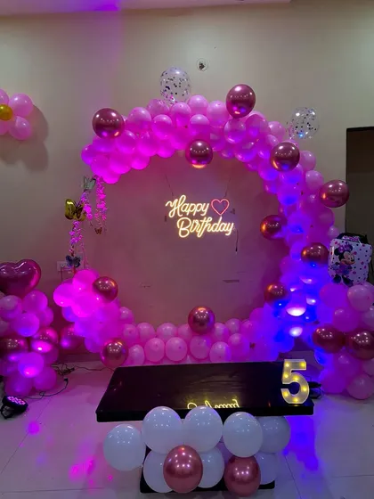 A full view of the sophisticated 5th birthday home decoration, featuring a circular backdrop, neon sign, and marquee number.