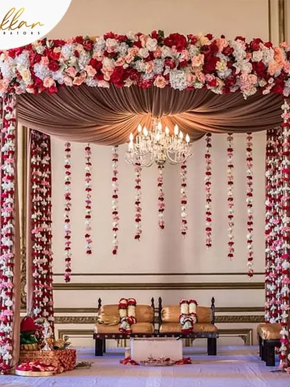 A beautiful canopy-style mandap created with red and white roses. The hanging floral strings and central chandelier add a touch of classic romance and elegance.