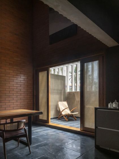 A bedroom in the Brick House, where exposed brick walls and a large sliding door with a woven screen create a warm, tactile, and private retreat.