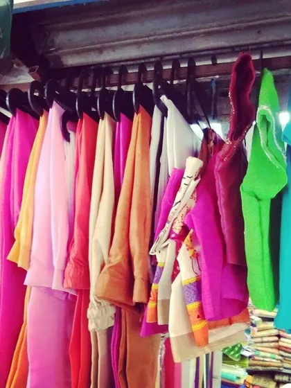 A colorful array of blouses and suit pieces hanging in our shop. We take pride in the variety and quality of our work.
