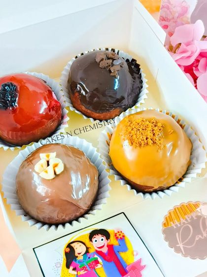 These brioche donuts are a fun and delicious Rakhi gift. This box of four includes assorted flavors like chocolate glazed, Biscoff, Nutella, and strawberry, perfect for a sweet surprise.