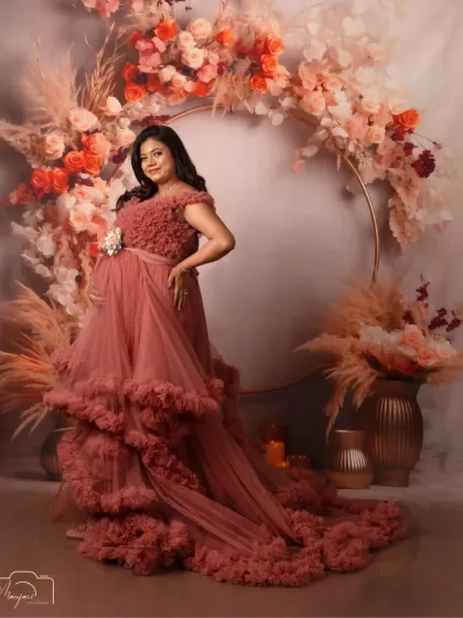 A confident and glowing portrait. The rich color of the gown stands out beautifully against the soft, earthy tones of the floral ring setup.