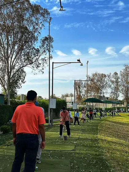 A coach in an orange shirt watches over the range, ensuring everyone has what they need for a great session.