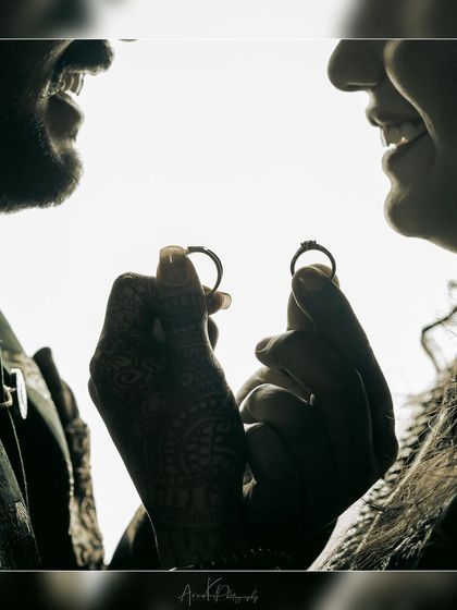 A creative silhouette shot of a couple holding their engagement rings, symbolizing their union.
